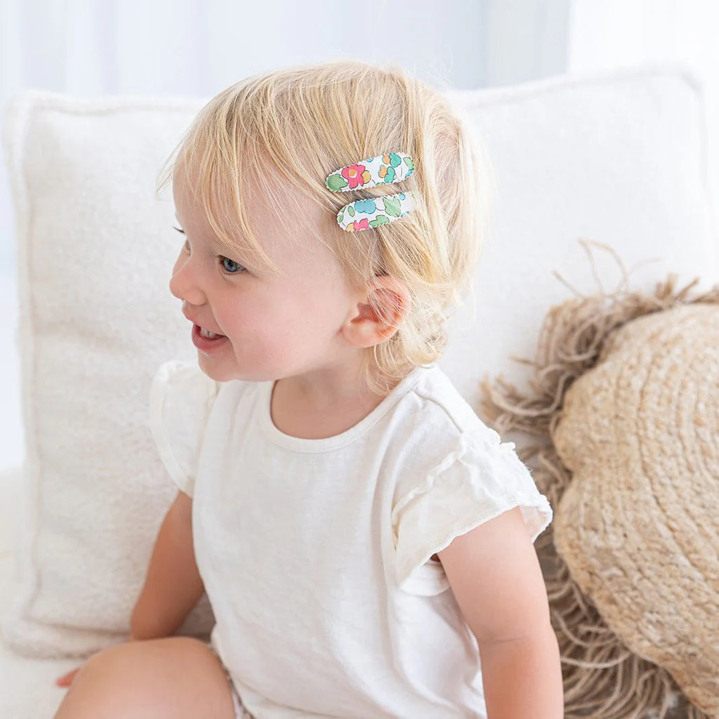 Child with floral hair clip sitting on a white couch