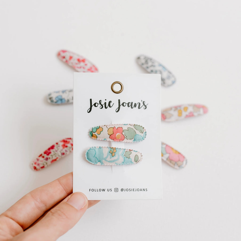 Colorful hair clips on a 'Josie Joan's' branded card held by a hand against a white background.