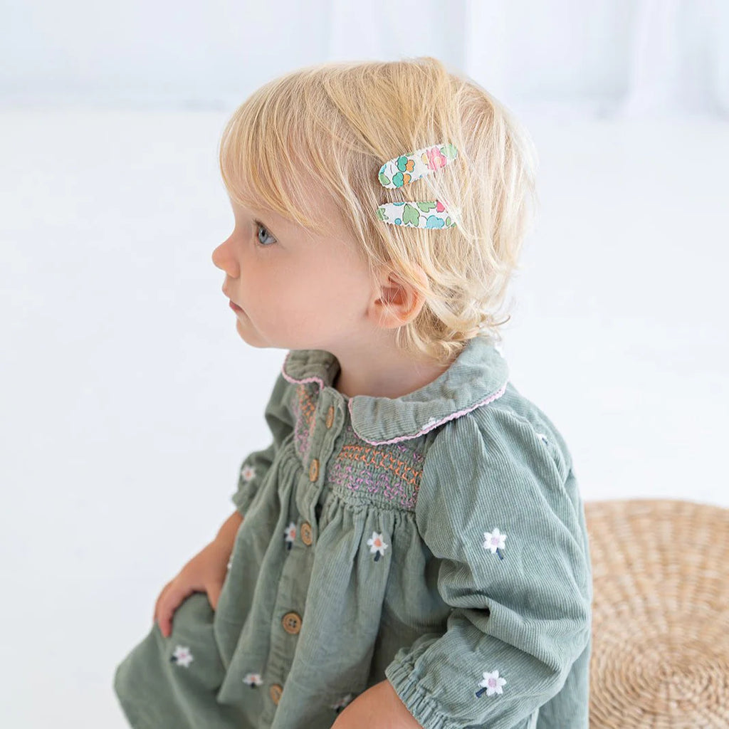 Young girl wearing a green dress with floral details on a light background