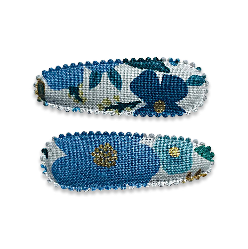 Two fabric-covered snap hair clips with a floral pattern and scalloped edge detail.