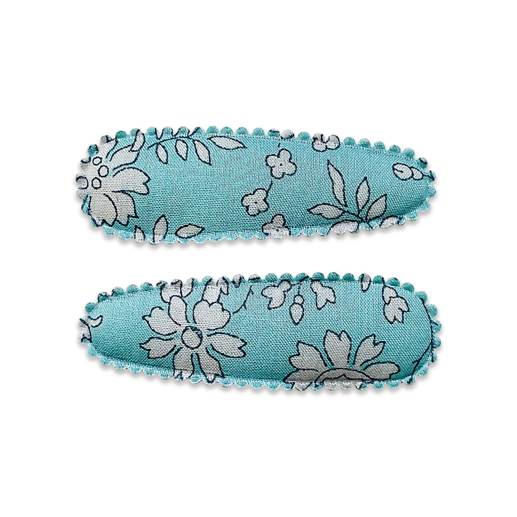 Two fabric-covered snap hair clips with a floral pattern on a light blue background.