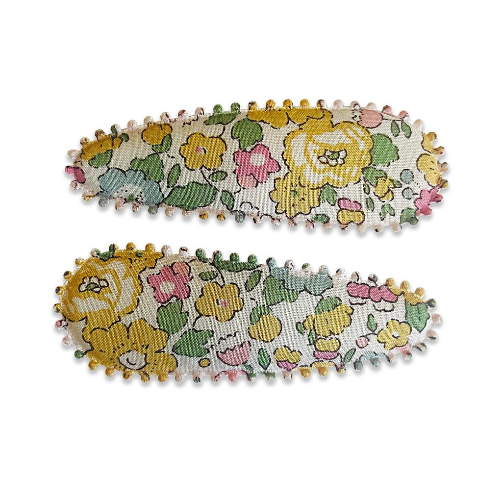 Two fabric-covered snap hair clips with a floral pattern and scalloped edge detail.