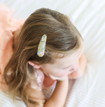 Child with a decorative hair clip on a soft white background