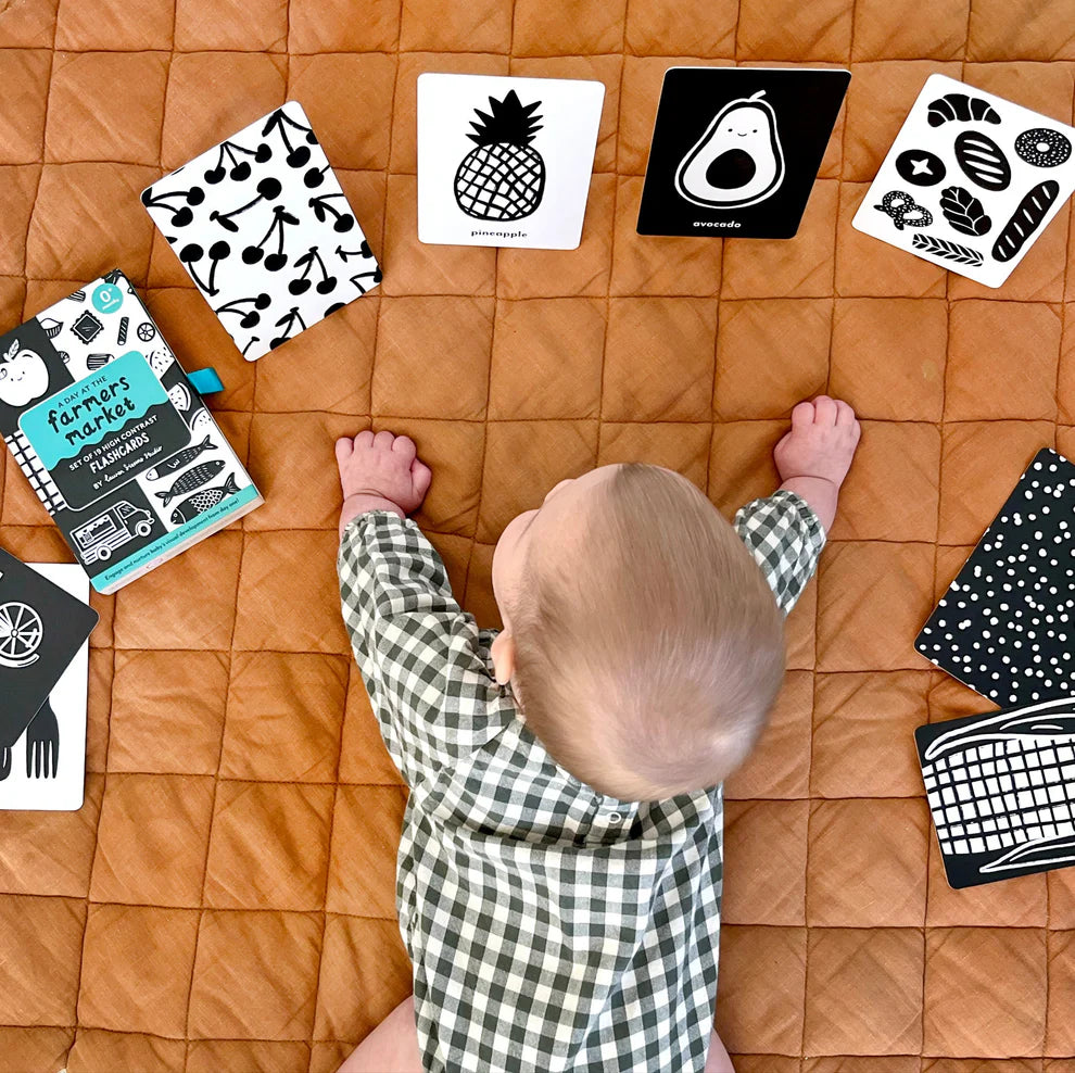 Baby playing on blanket with high contrast flashcards during tummy time