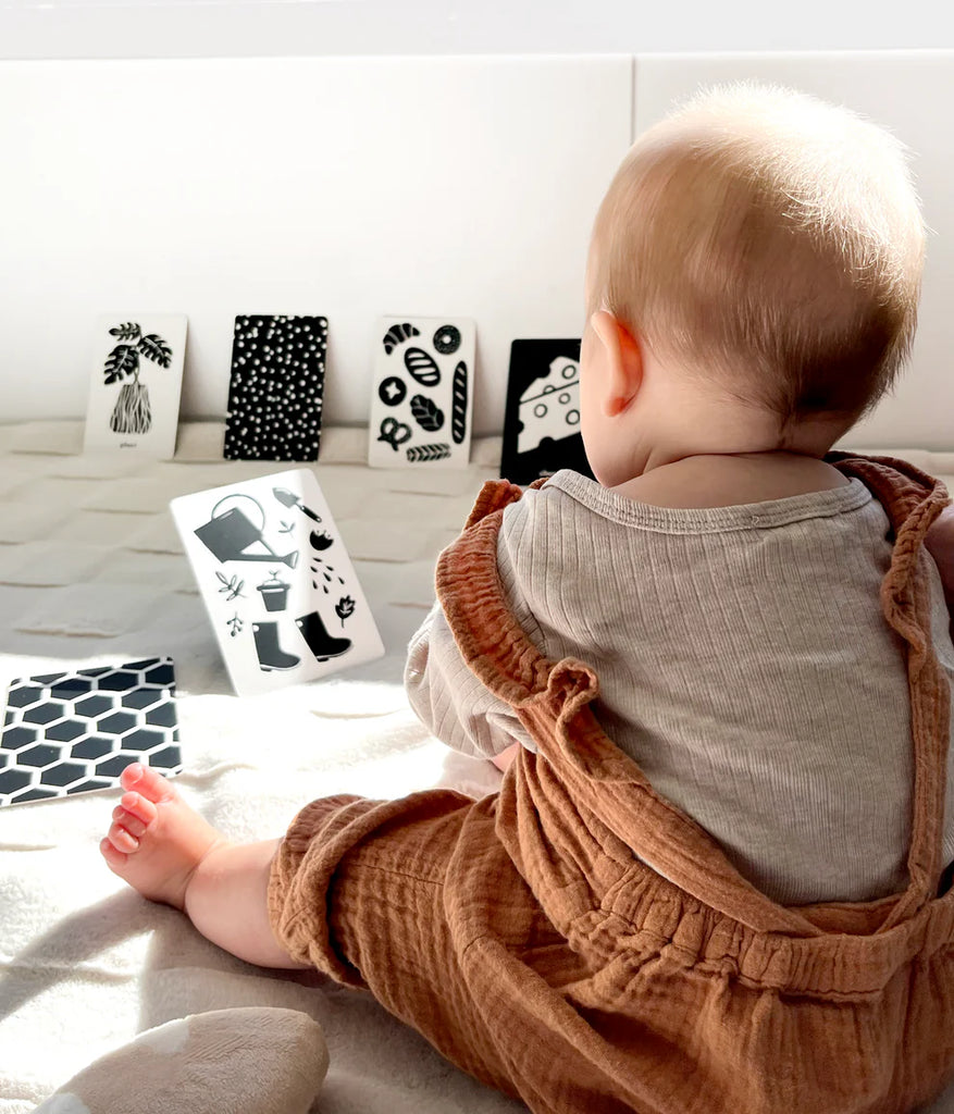 Newborn seated with high contrast flashcards propped open during visual play session