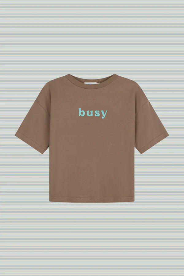 Flat lay of Lenn Label Busy Tee in Tanj, featuring 'busy' text on the front in blue.