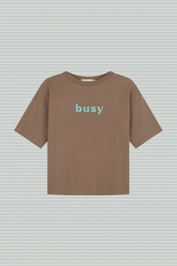 Flat lay of Lenn Label Busy Tee in Tanj, featuring 'busy' text on the front in blue.
