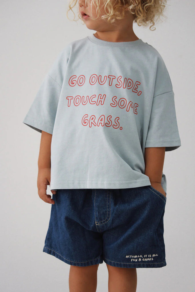 Child standing in Lenn Label Fun & Games shorts and 'Go Outside, Touch Some Grass' t-shirt, front view.