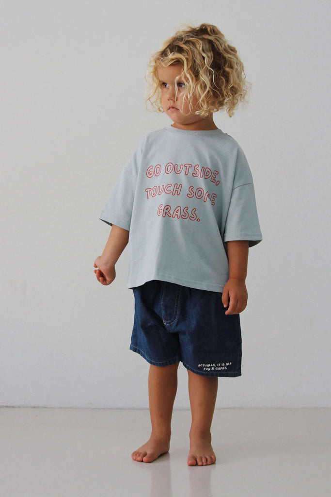 Full-body image of a child wearing Lenn Label Fun & Games shorts paired with a relaxed slogan t-shirt, barefoot against white backdrop.