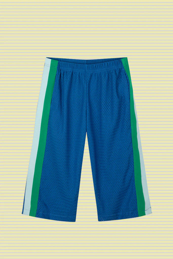 Flat lay of the Sports Pant in Sea, displayed against a pale yellow striped background. The pants feature a cobalt blue perforated sports mesh base with bold seafoam green and pale blue vertical side stripes, finished with an elastic waistband.