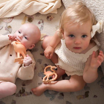 Two babies playing with toys on a patterned blanket