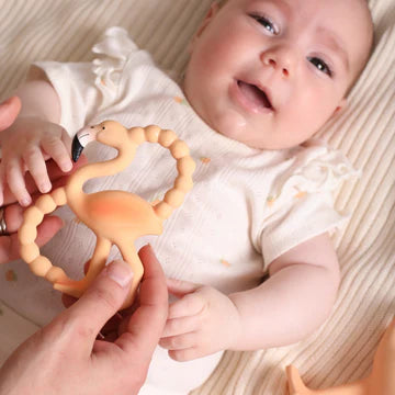 Baby holding a silicone teether with a smiling expression