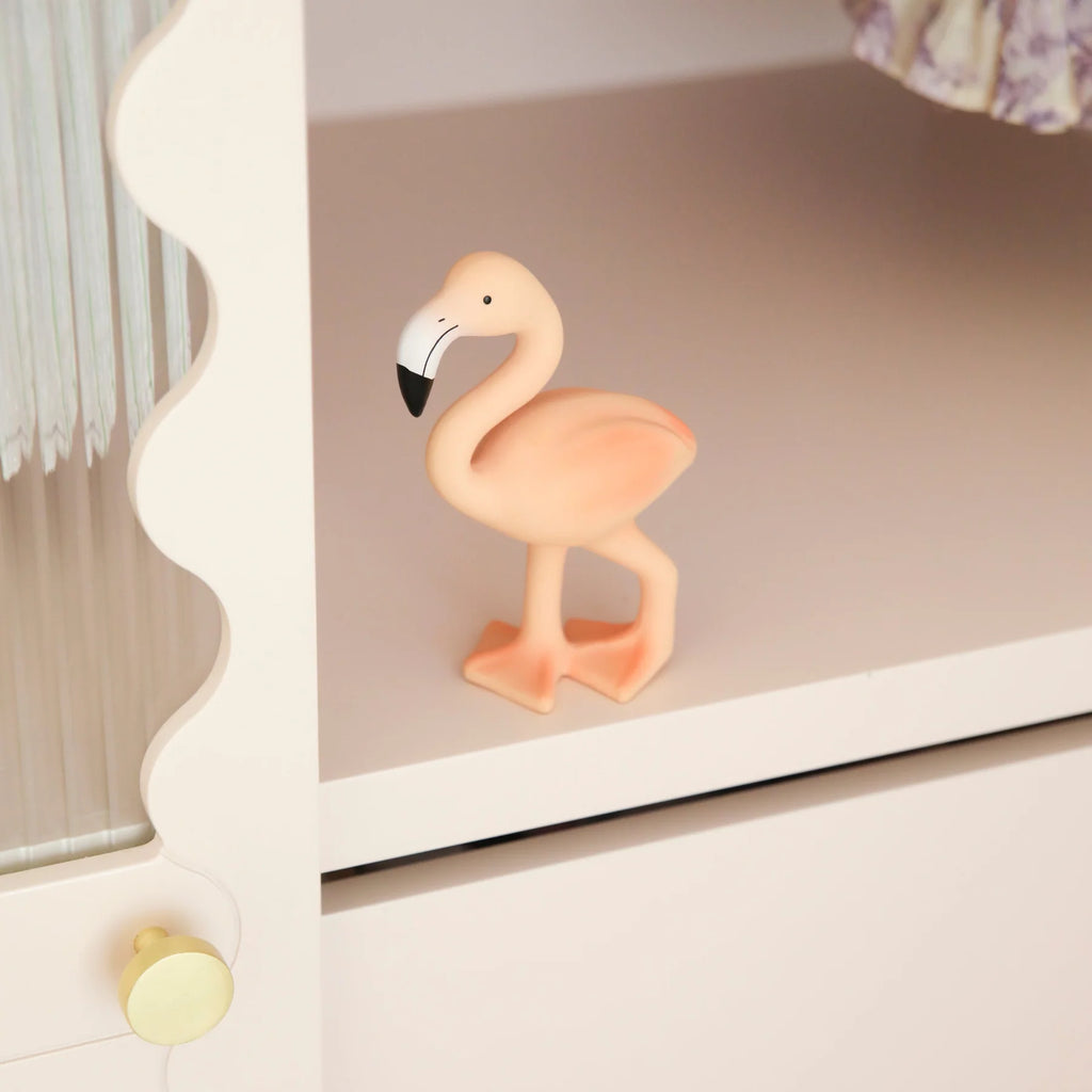 Pink flamingo figurine on a shelf with a neutral background
