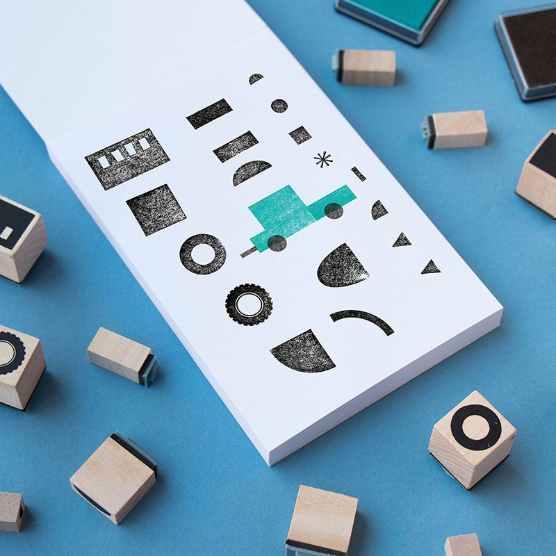 Close-up of Londji BAM! Create Your Transports wooden stamps and printed vehicle shapes on paper.