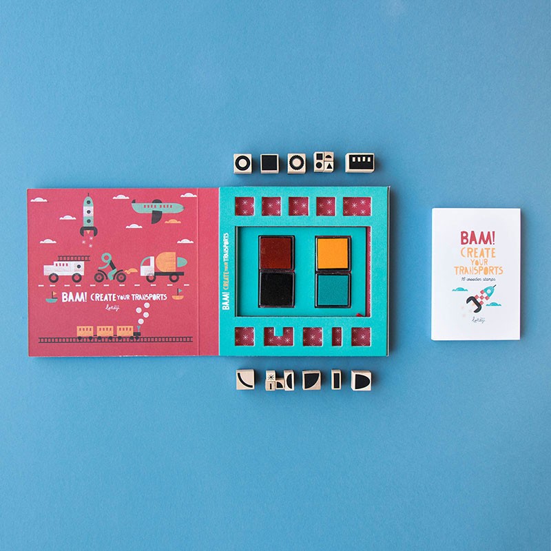 Londji BAM! Create Your Transports set open on blue surface with ink pads, booklet, and wooden stamps.