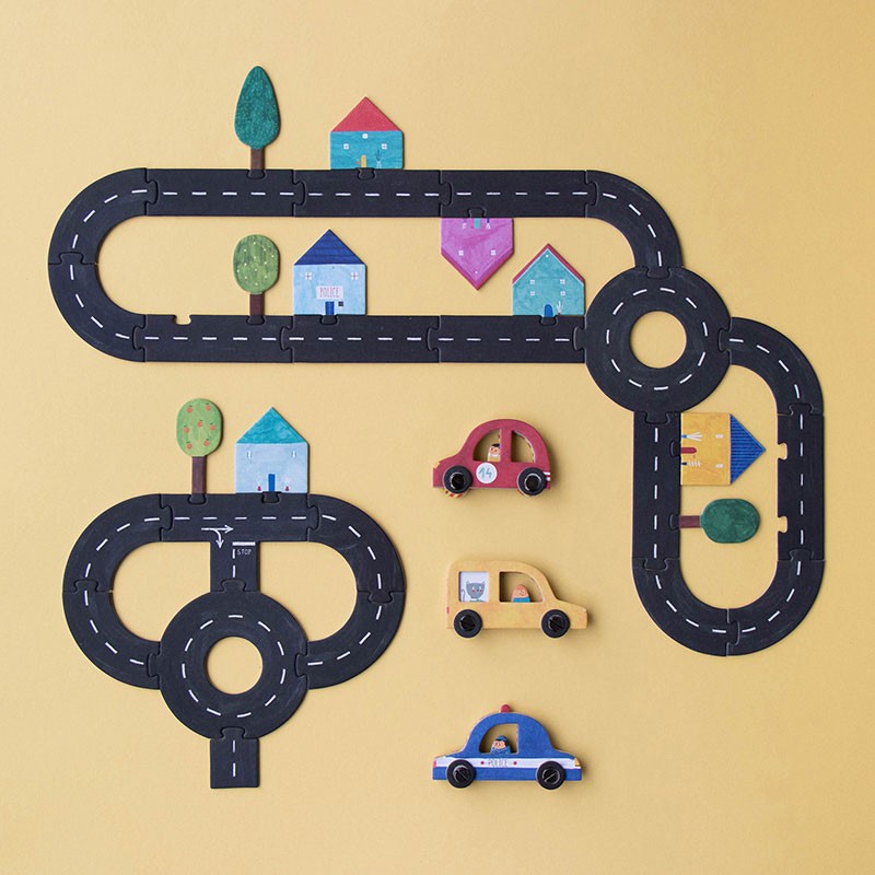 Londji Roads puzzle game assembled with black road pieces, colorful houses, trees, and three small wooden cars.