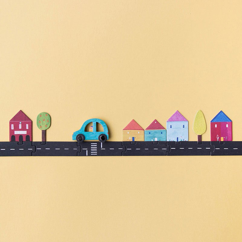 Assembled Londji Roads puzzle showing a long road with colorful illustrated houses, trees, and a blue car.