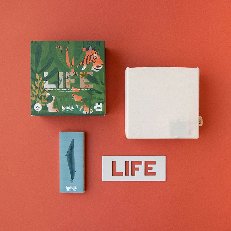 Contents of Londji Life Puzzle set including the box, puzzle bag, guide, and LIFE cutout displayed on a red background.