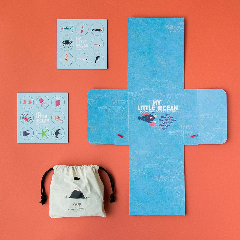 Contents of Londji’s My Little Ocean Pocket Puzzle displayed — ocean-themed cards, blue fold-out board, and cotton drawstring storage bag.