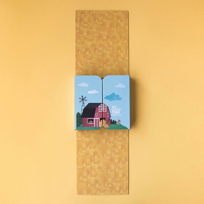 Open packaging of Londji’s My Little Farm Puzzle showing the barn illustration and neatly folded yellow dotted interior design.