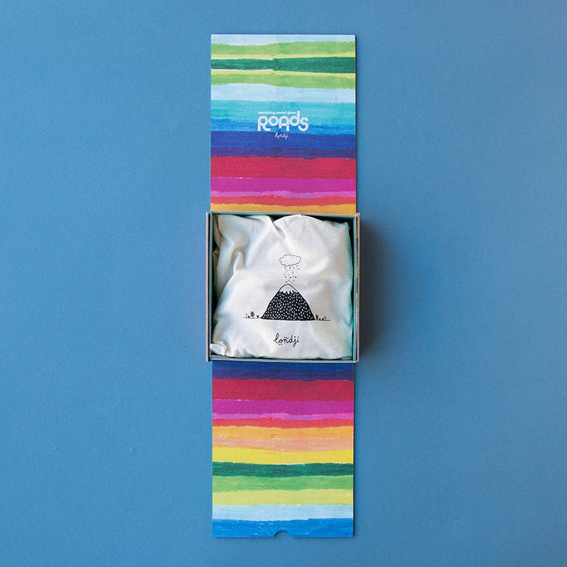 Open Londji Roads Pocket Game box showing a cloth storage bag with a volcano design inside colorful striped packaging.