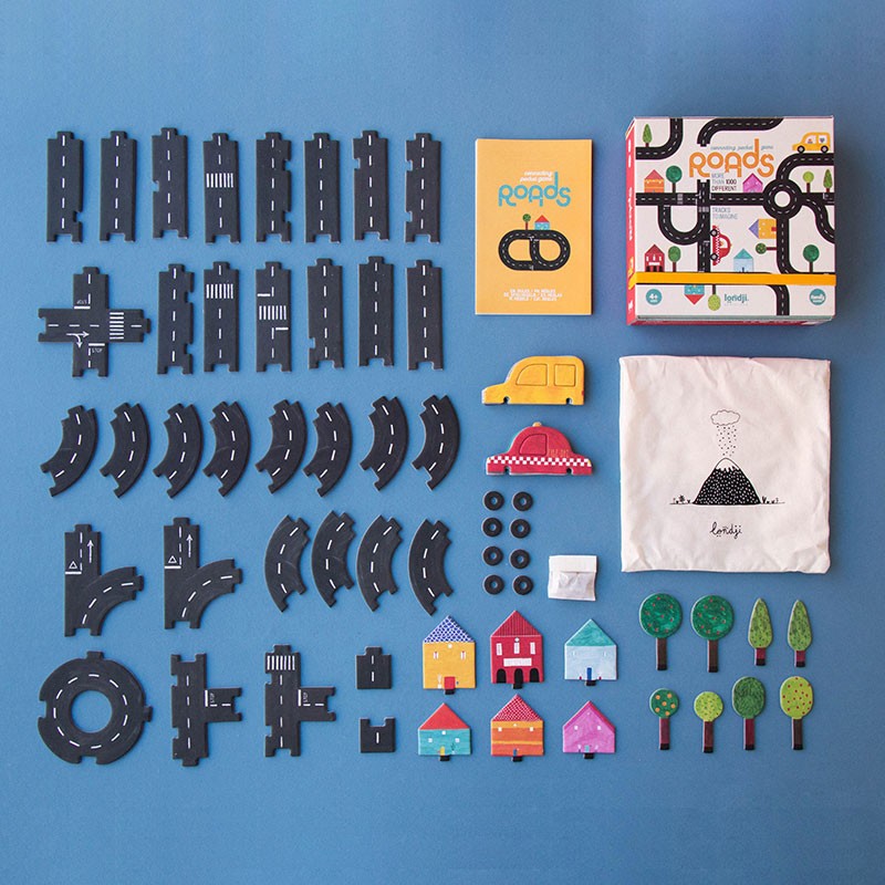 Londji Roads Pocket Game pieces laid out, including roads, cars, houses, and trees on a blue surface.