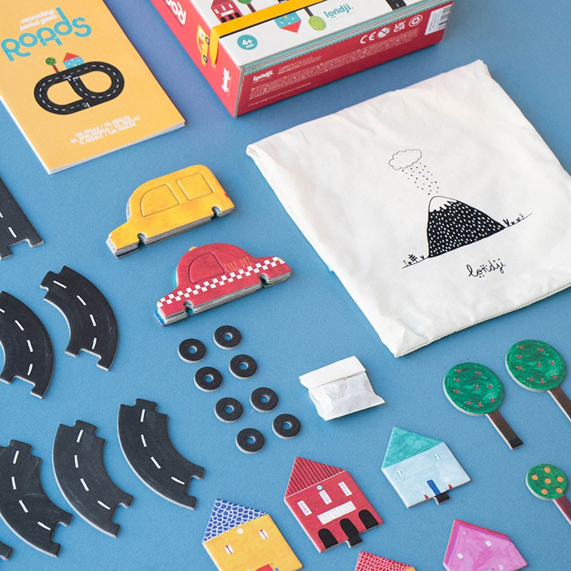 Close-up of Londji Roads Pocket Game components including cars, roads, and wooden houses next to the box.