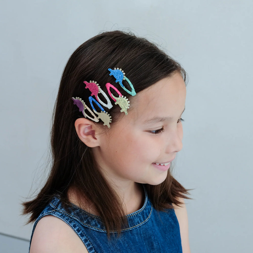 Girl wearing colorful glitter dinosaur hair clips – sparkly stegosaurus accessories for kids who love dinos, perfect fun hair styling idea.
