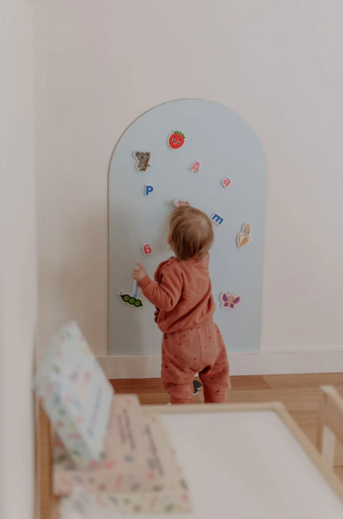 Toddler placing colourful alphabet magnets on a magnetic board during independent play with the MagPlay Alphabet Kit.