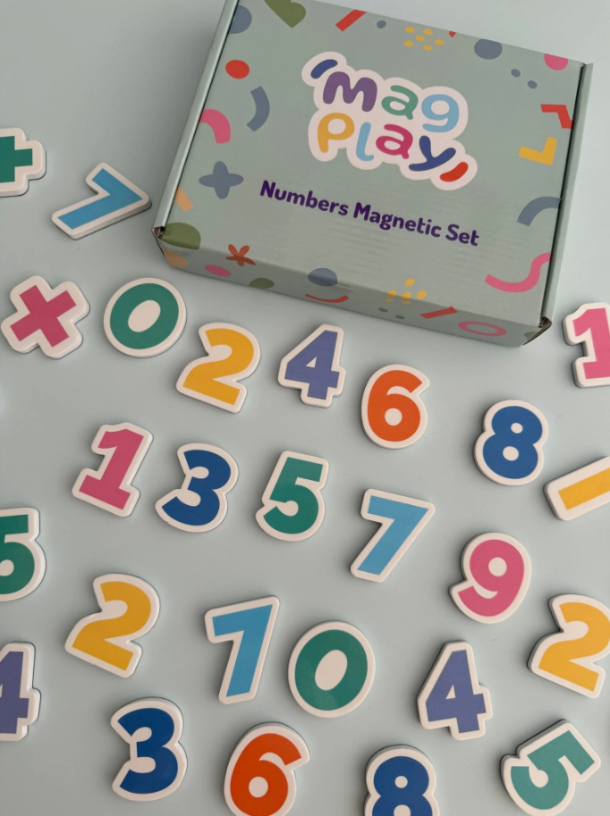 Flat lay of the MagPlay Numbers Magnet Kit box surrounded by colourful number magnets on a light grey surface.