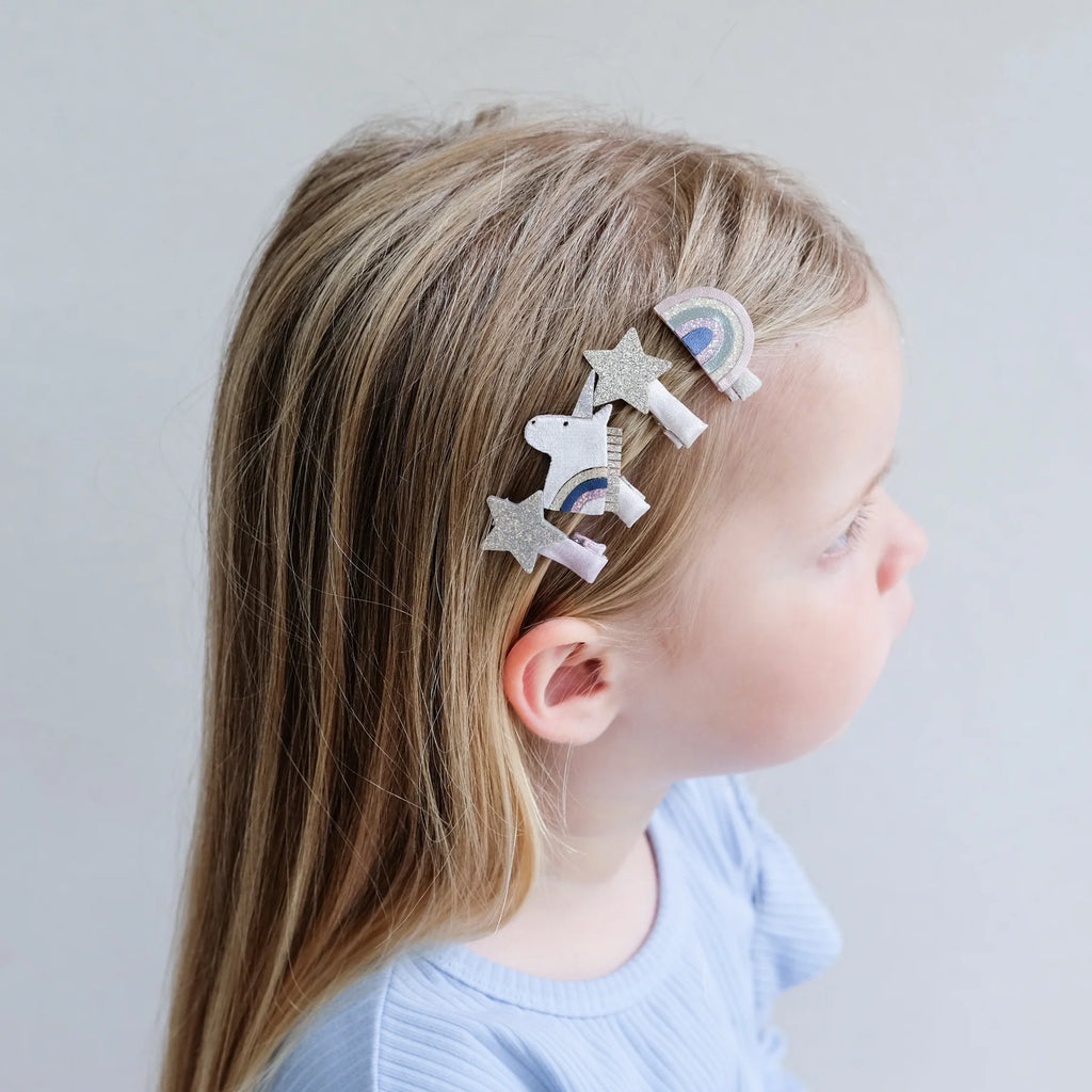 Girl wearing Mimi & Lula Celeste Mini Clips unicorn and star designs on the side of her hair.