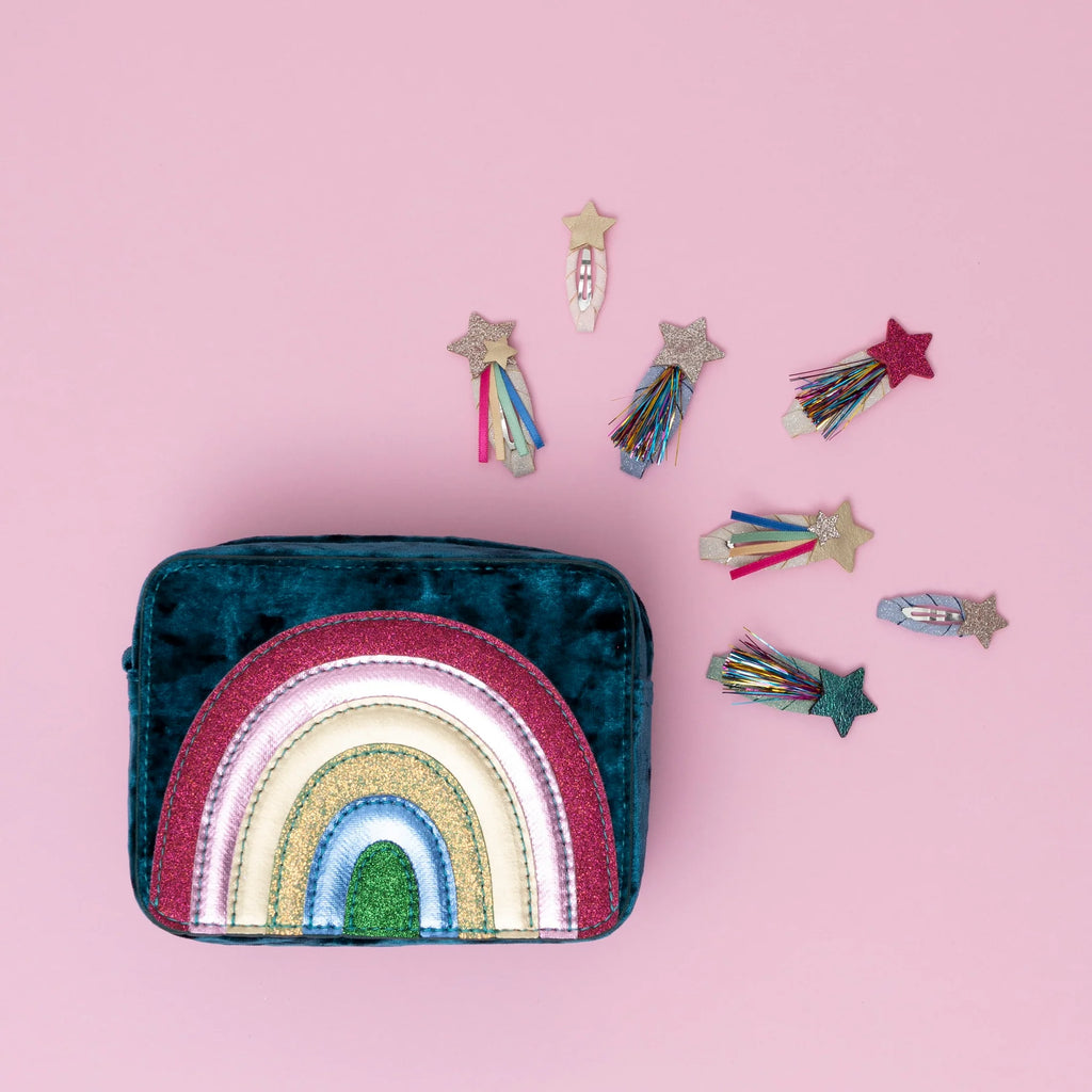 Velvet rainbow bag surrounded by Mimi & Lula Disco O’Bow Clips in glitter star and rainbow shooting designs.