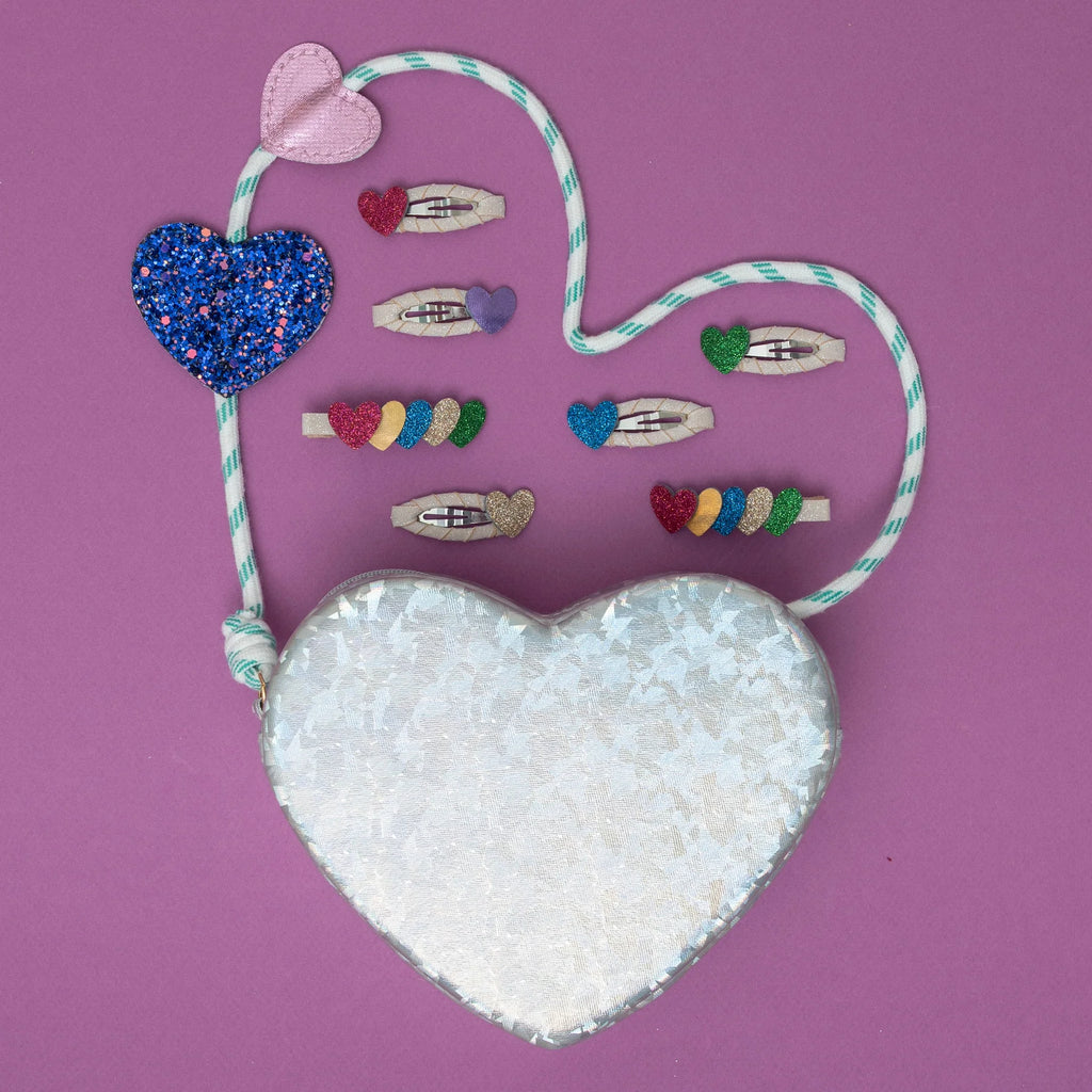 Mimi & Lula Jazzy Heart hair clips styled with glitter heart bag on pink background – fun and colorful kids hair accessories set.