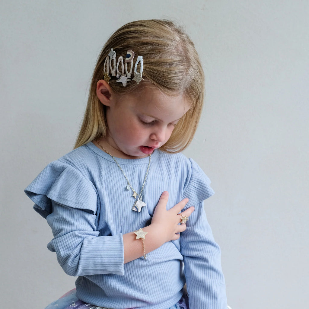 Little girl wearing Mimi & Lula Celeste Mini Clic Clacs and matching gold star necklace and bracelet.
