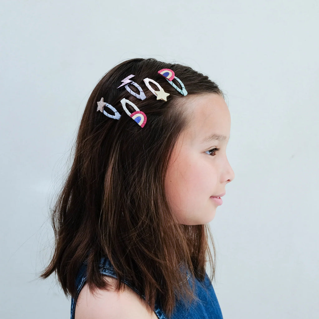 Young girl wearing Mimi & Lula Rainbow Mini Clic Clacs with glitter rainbows, stars, and lightning bolts in her hair.