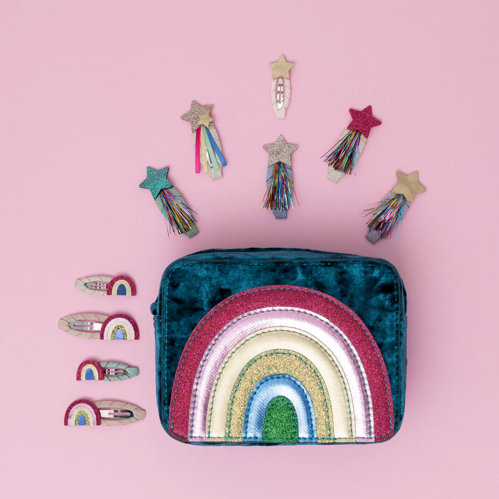 Flat lay of Mimi & Lula Rainbow Mini Clic Clacs and a velvet rainbow bag with glitter stars and pastel shooting stars.
