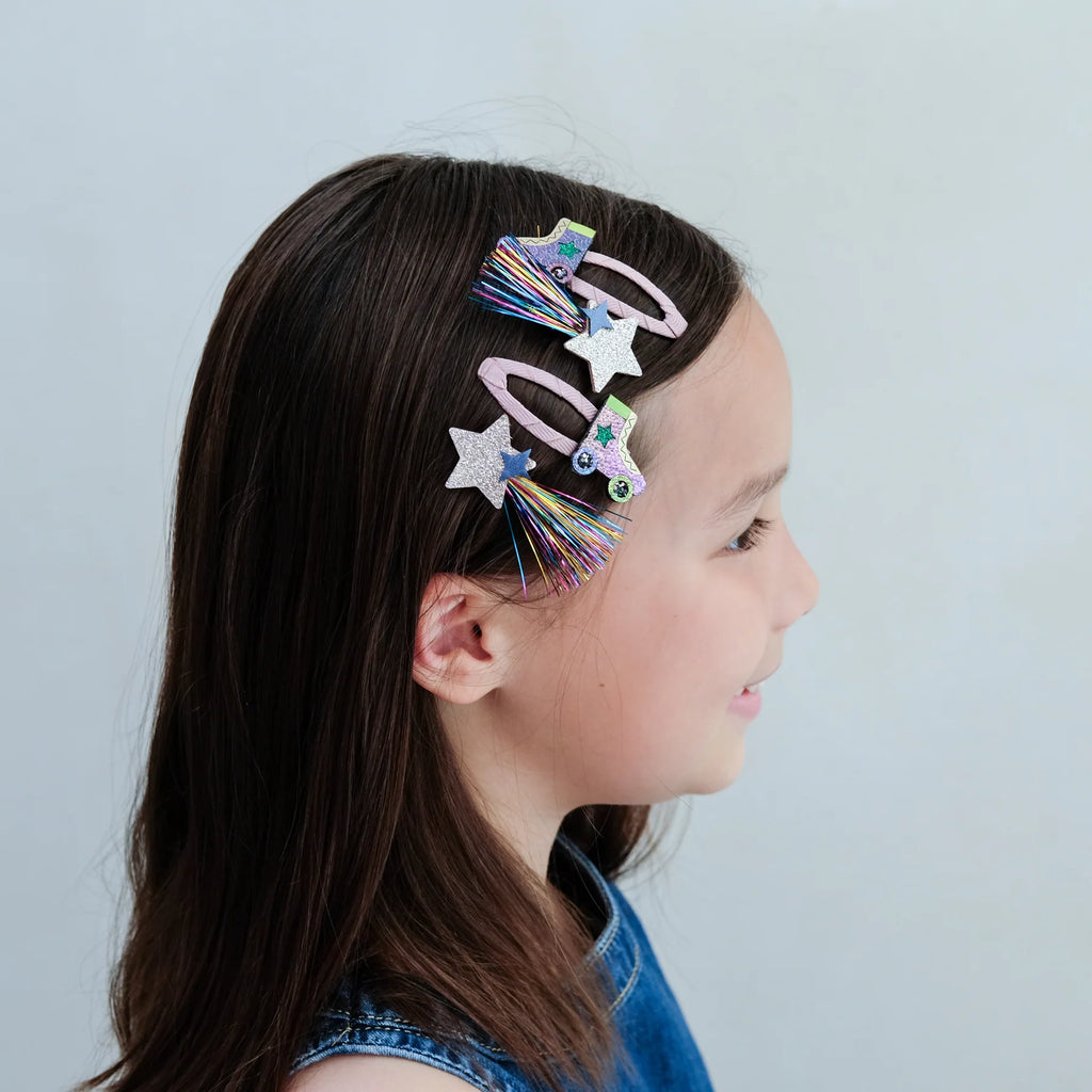 Girl wearing Mimi & Lula Rollerskate Hair Clip Set with glitter stars and pastel skates in her hair.