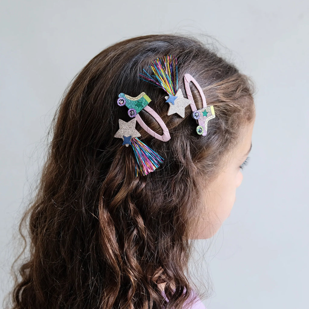 Girl with curly hair wearing Mimi & Lula Rollerskate Hair Clip Set featuring rainbow stars and rollerskates.
