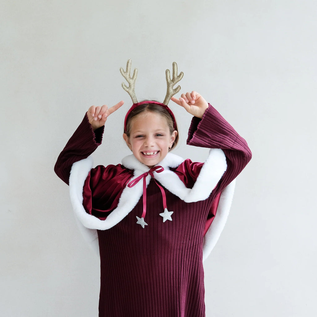 Little girl wearing sparkly gold Rudolph antlers headband with velvet alice band – festive Christmas outfit accessory