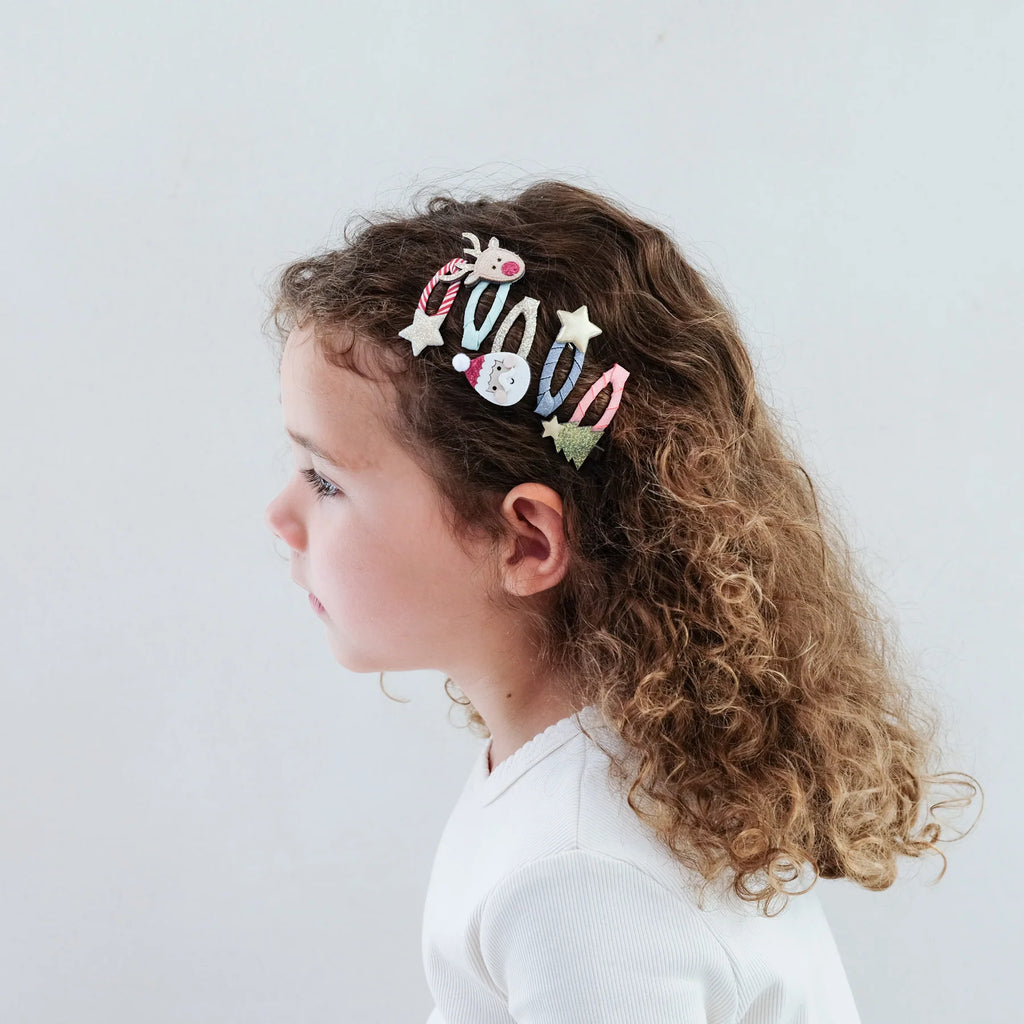 Child wearing Mimi & Lula Santa & Rudolph Clic Clacs styled in curly hair for a festive holiday look.