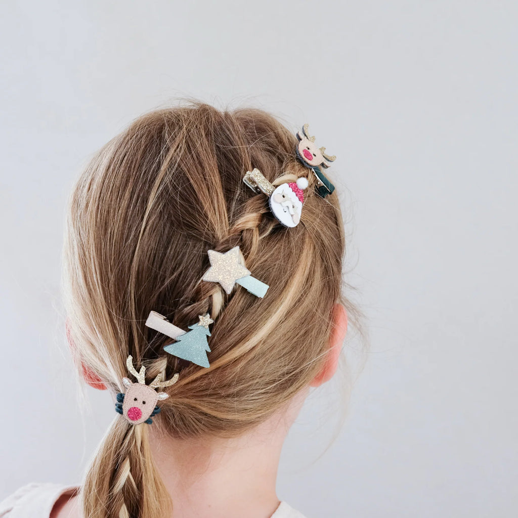 Girl with braided hair wearing Mimi & Lula Christmas clips featuring Santa, reindeer, and stars.