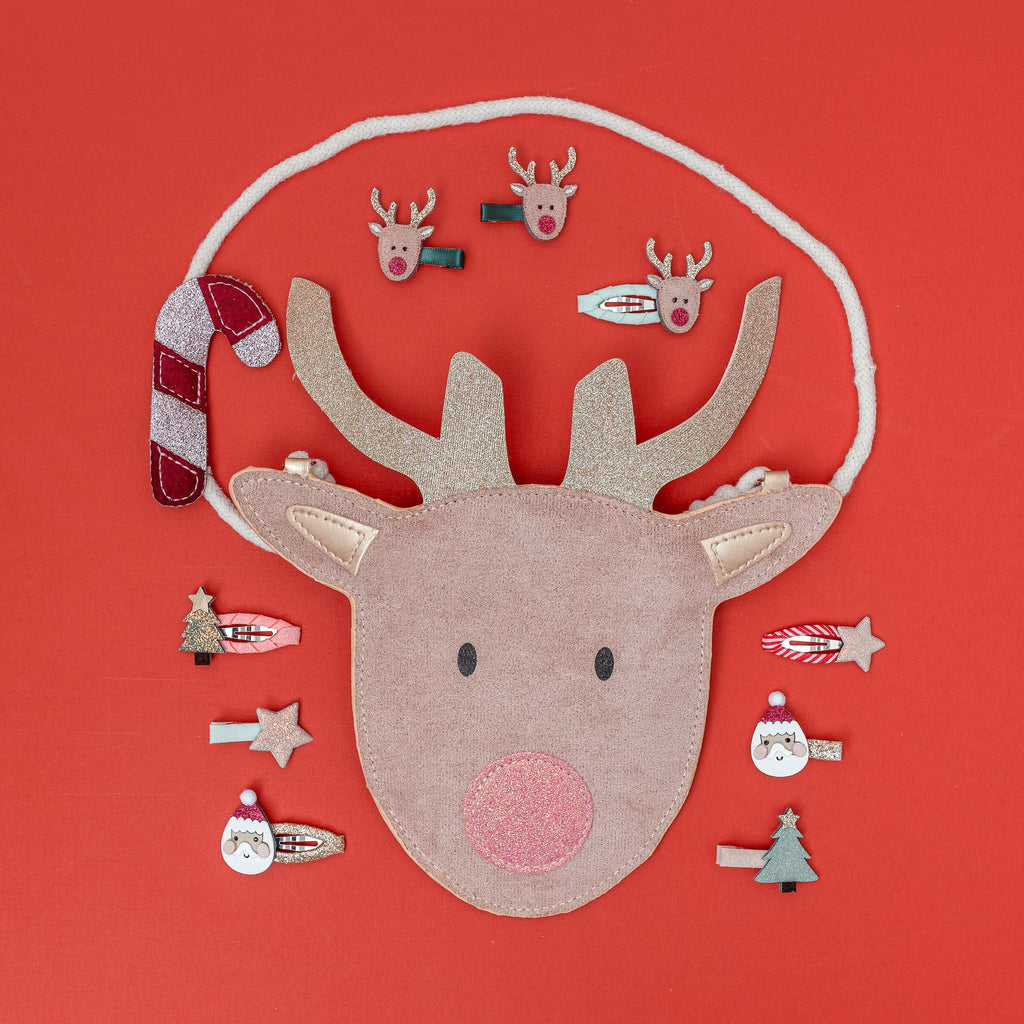 Flat lay of Mimi & Lula Santa & Rudolph clips and reindeer bag on red background.