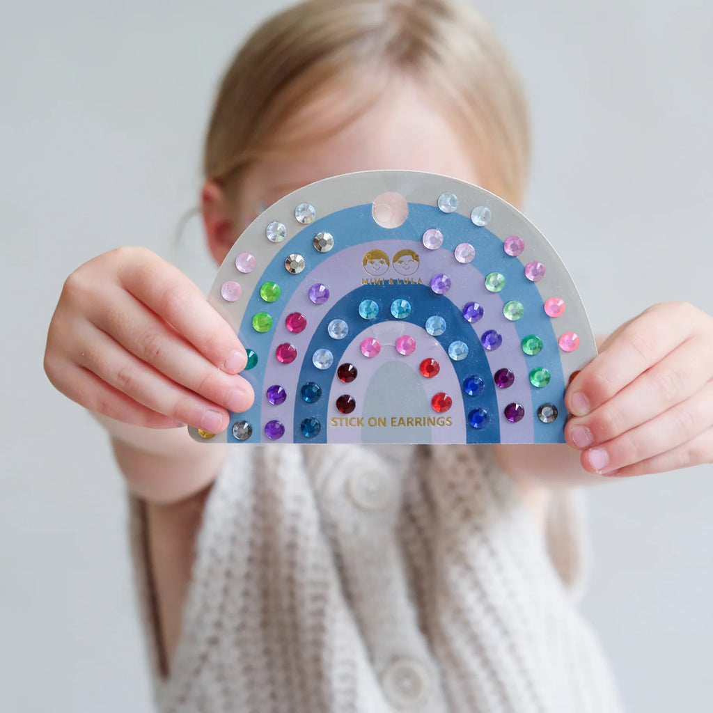 Child holding Mimi & Lula rainbow stick-on earrings sheet