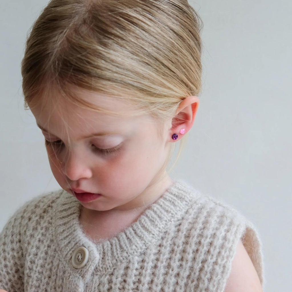 Girl wearing pink and purple Mimi & Lula stick-on earrings