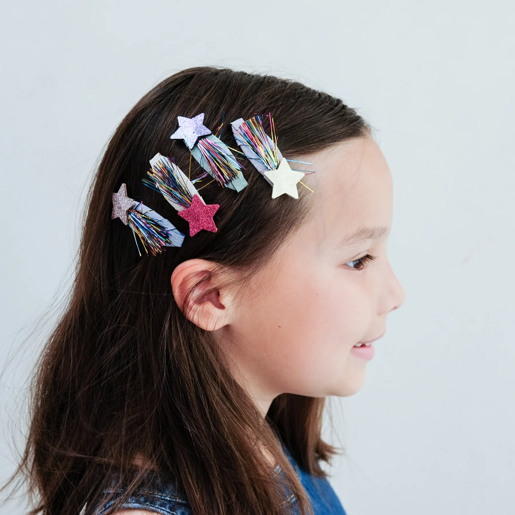 Girl wearing Mimi & Lula glitter star hair clips with rainbow tinsel strands in her hair.
