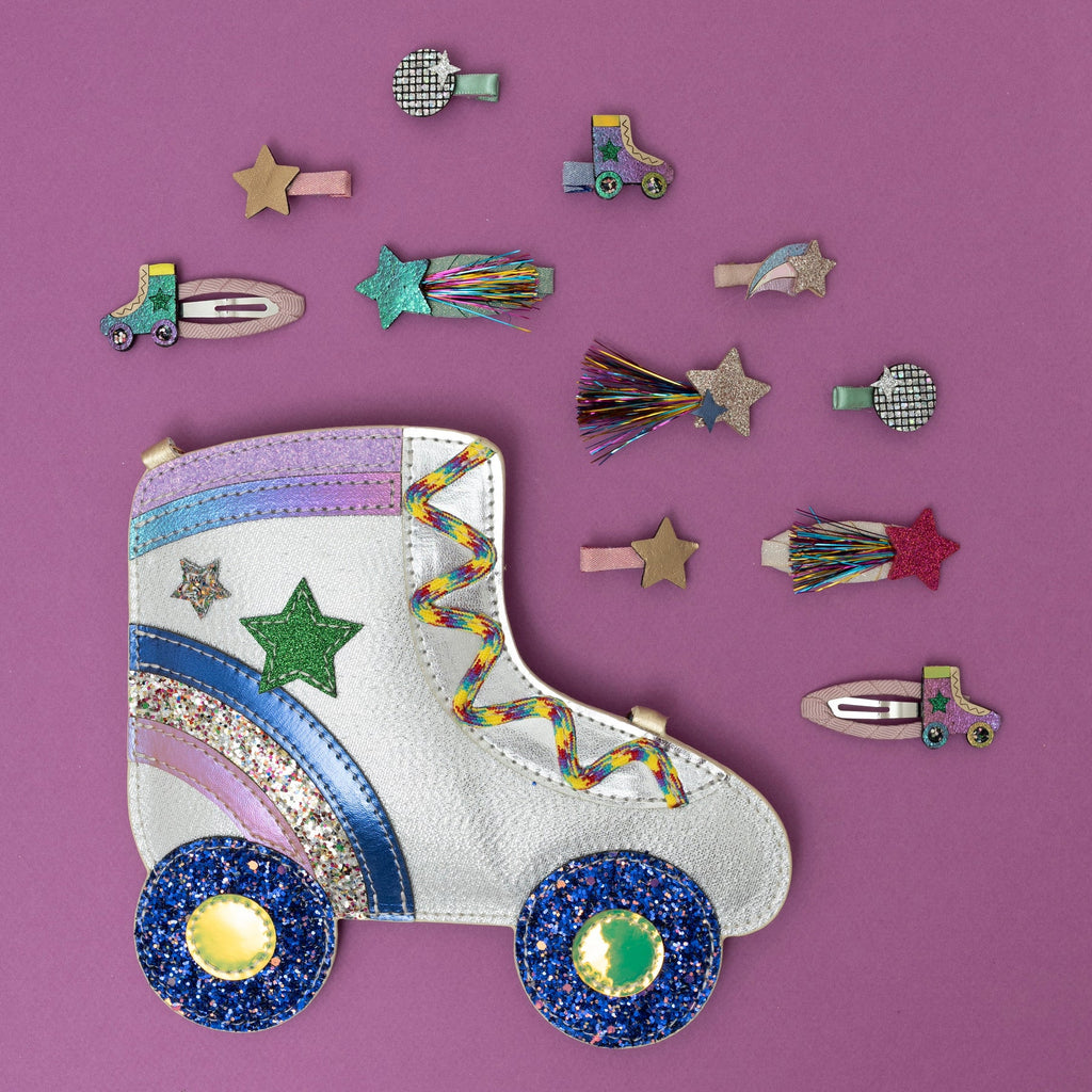 Mimi & Lula Tinsel Star hair clips and roller skate bag displayed on a pink background.