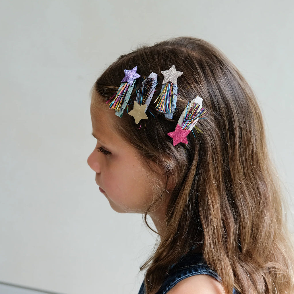 Girl’s side profile showing colorful tinsel star hair clips by Mimi & Lula in her hair.