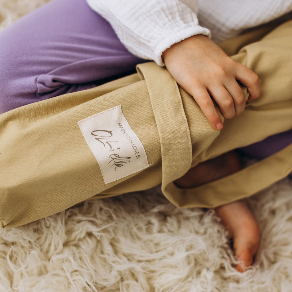 Close-up of toddler holding folded honey stroller carry bag – Child gripping cotton canvas storage bag for honey stroller.