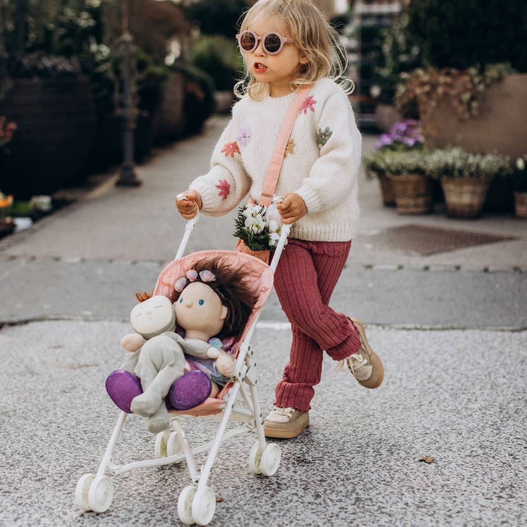 Toddler pushing Dinkum Doll in Sollie Stroller outdoors – Child walking on pavement while pushing stroller with doll inside.