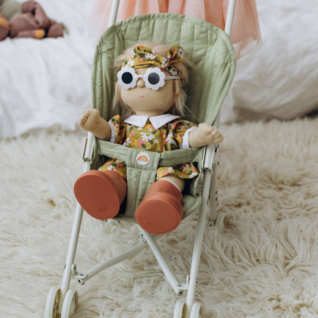 Toddler pushing Dinkum Doll in Sollie Stroller indoors – Child pushing doll pram across a rug with plush doll inside.